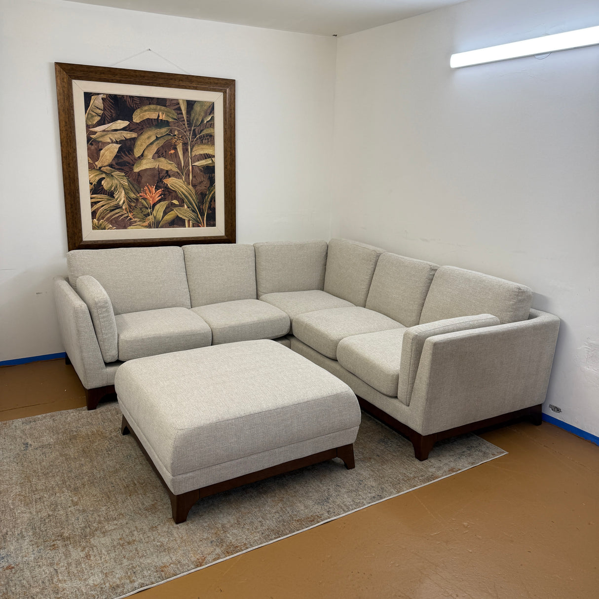 Chalk gray Article 88-inch sectional sofa with matching ottoman and walnut wood accents in a modern living room setting.