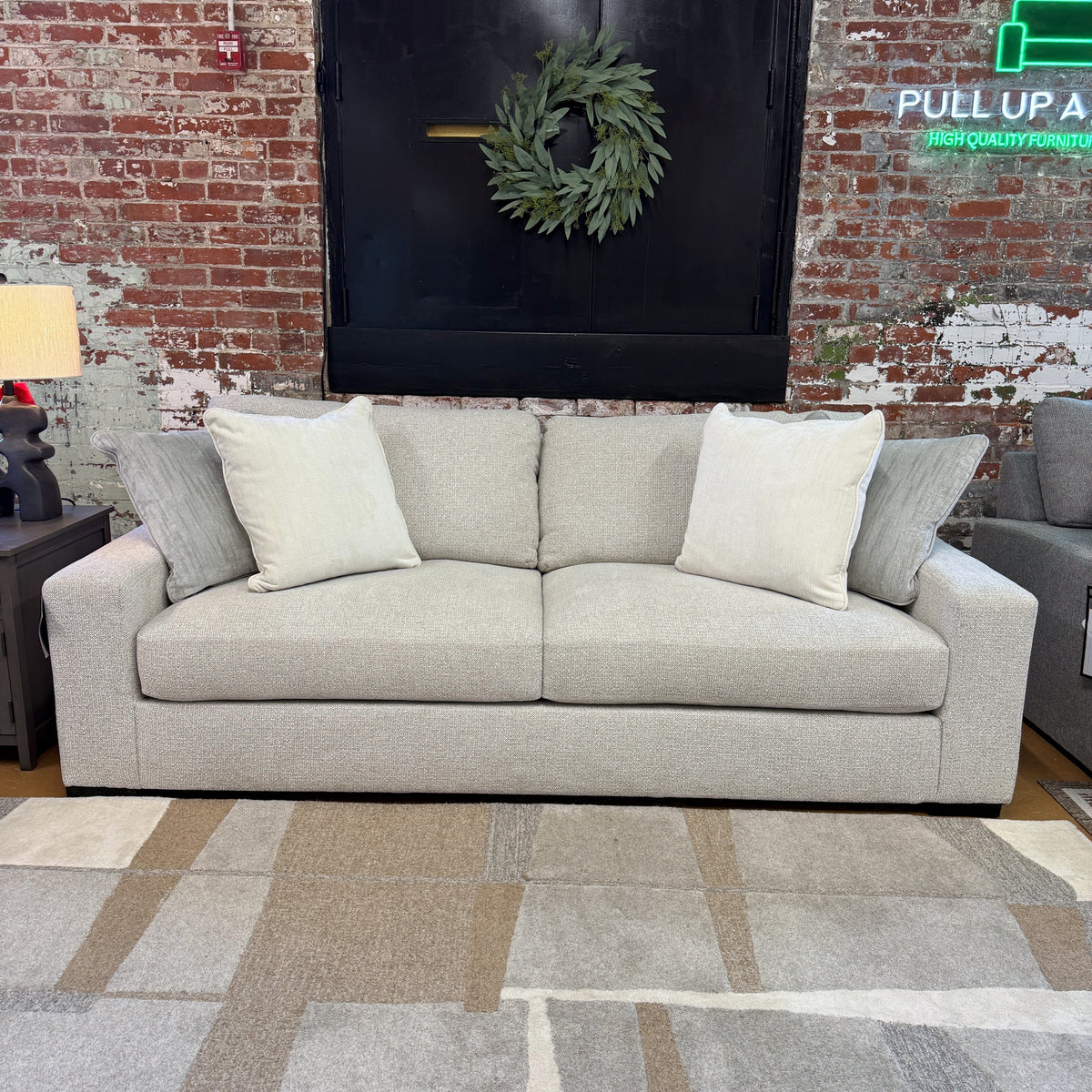 Ashley Furniture Hudson Sofa, plush beige fabric with cushioned armrests and wooden legs, shown from a front angle.