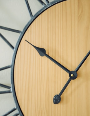 Ashley Furniture Brockett wall clock with a round, rustic design and black metal frame, hanging on a neutral-colored wall.
