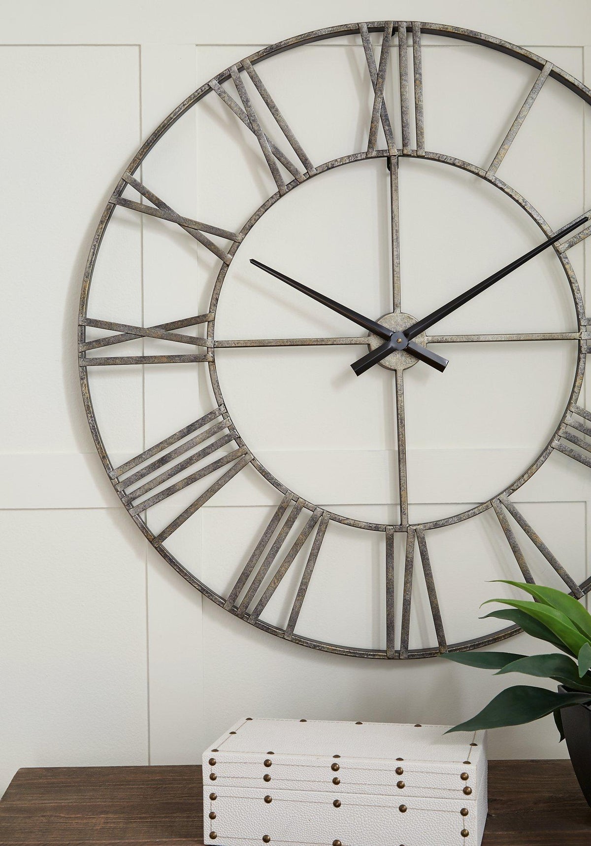 Ashley Furniture Paquita Wall Clock showing a sleek round design with black hour and minute hands on a light background.