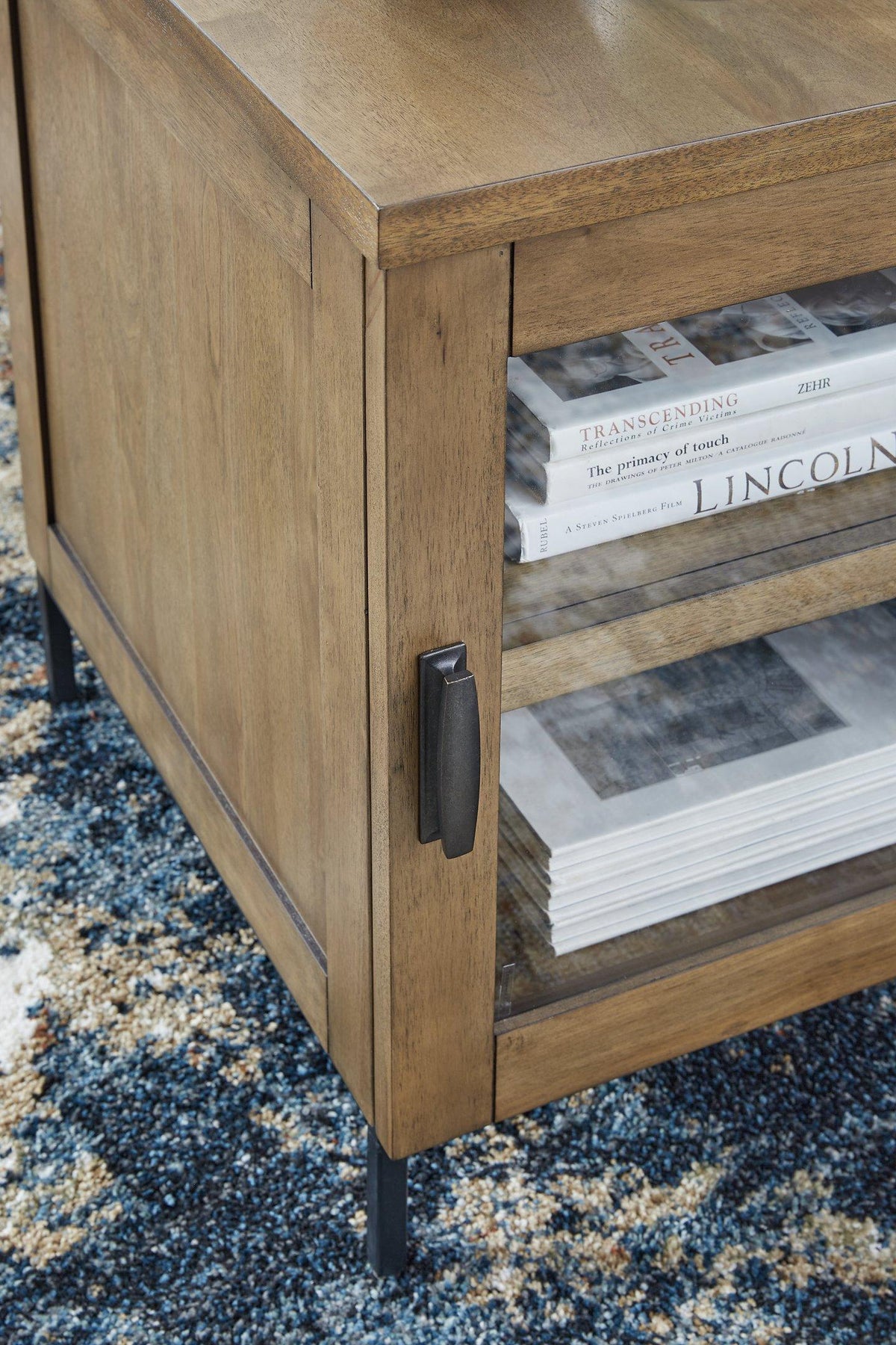 Ashley Furniture Torlanta chairside end table with wood finish and storage drawer, placed beside a sofa in a modern living room.