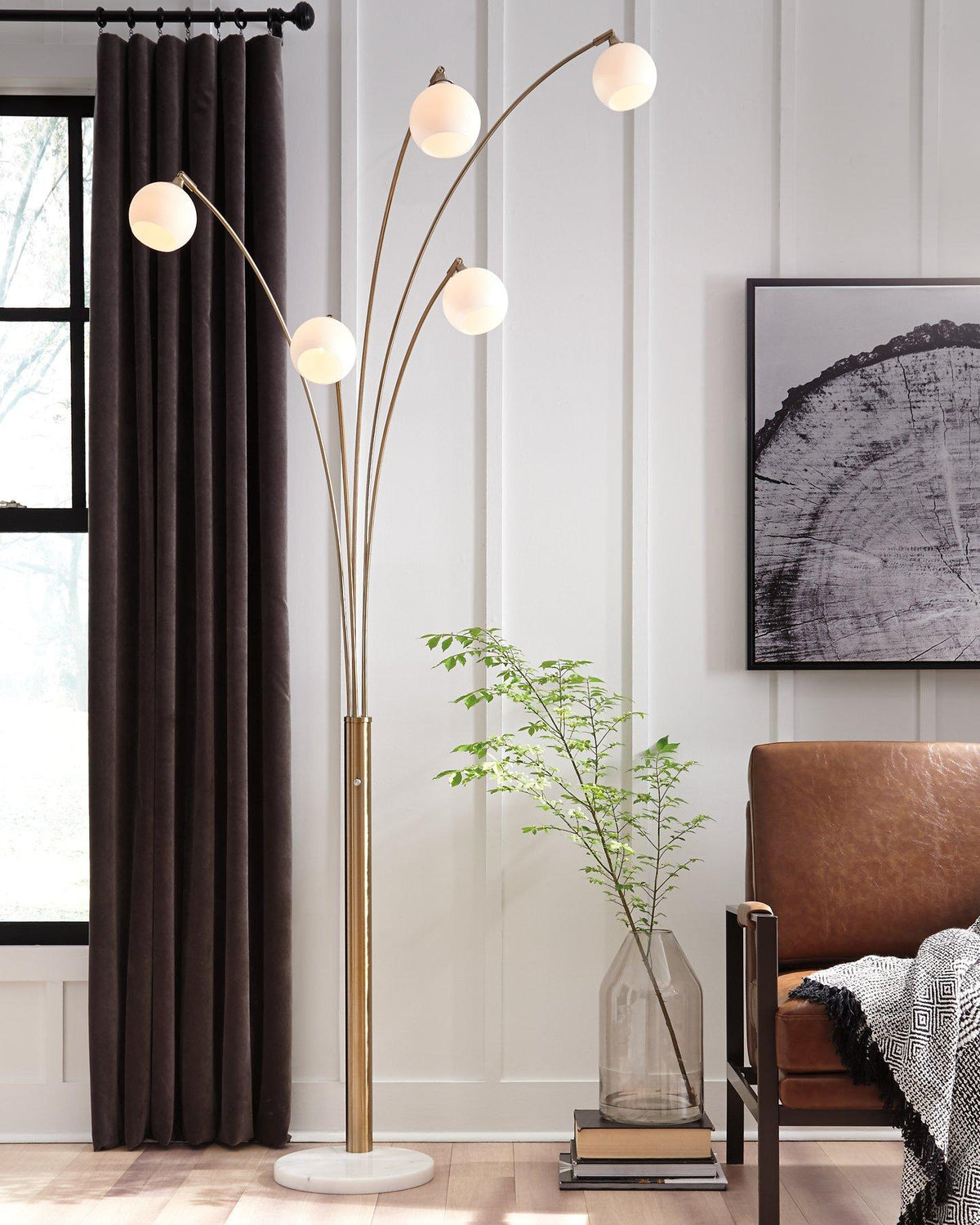 Taliya Arc Floor Lamp by Ashley Furniture with a sleek curved metal design and a modern lampshade, placed in a stylish living room setting.