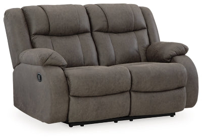 Ashley Furniture First Base reclining loveseat with plush cushions and a neutral fabric upholstery, shown from an angled view.
