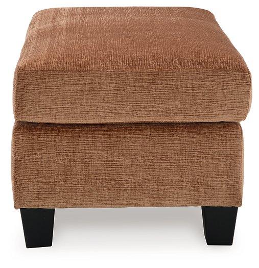 Ashley Furniture Amity Bay Ottoman with tufted fabric top and wooden legs, showcasing a stylish and functional living room accent piece.