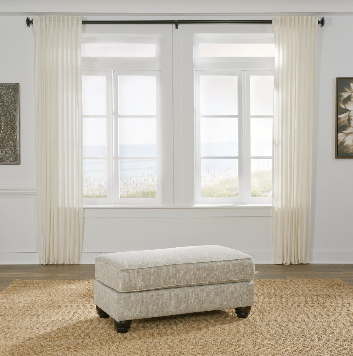 Ashanti ottoman by Ashley Furniture featuring a plush fabric surface and wooden legs, ideal for living room decor.