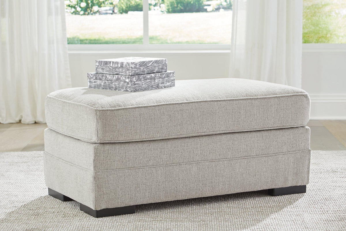 Ashley Furniture Eastonbridge Ottoman shown in a cozy living room setting, featuring a soft fabric upholstery and sturdy wooden legs.