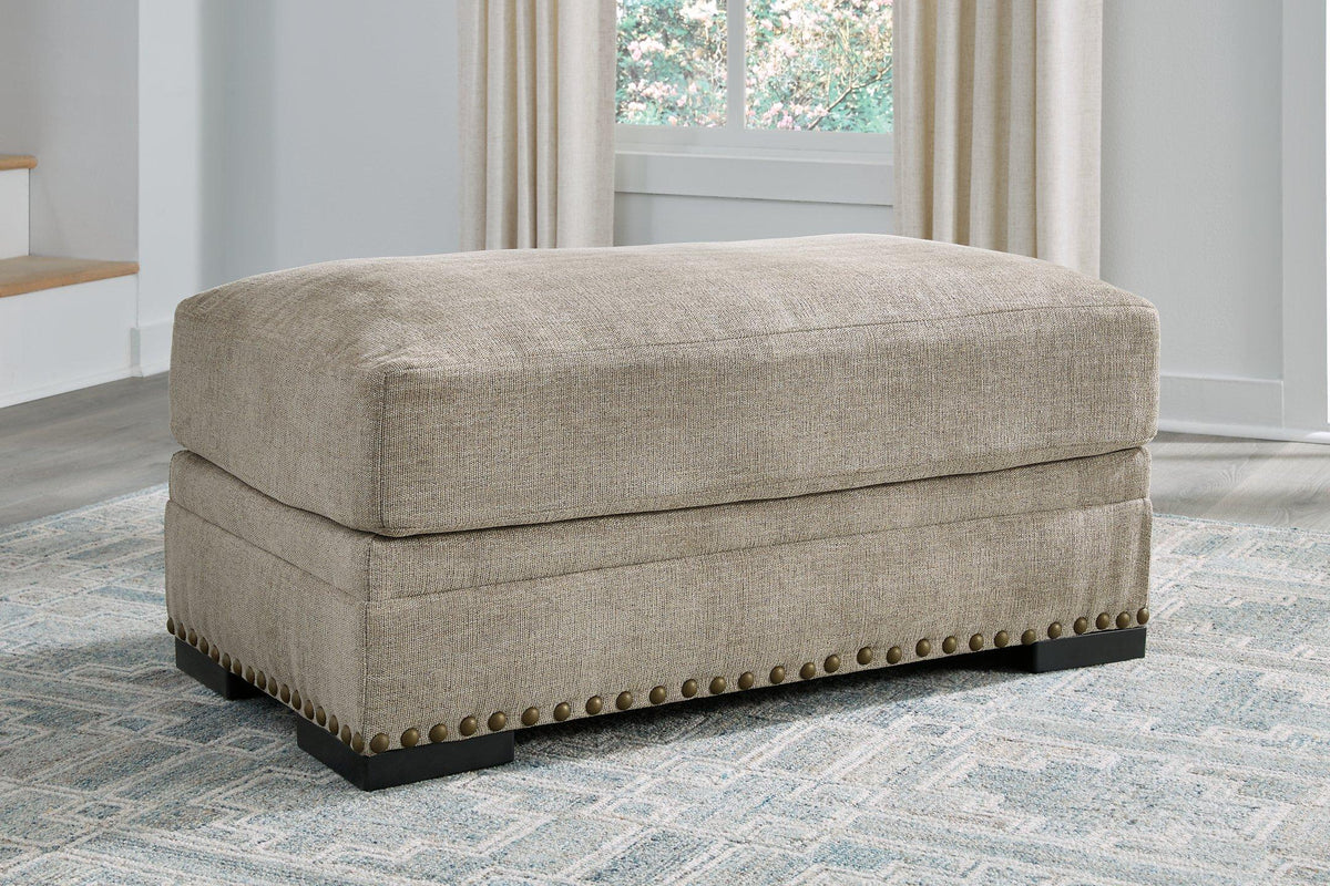 Ashley Furniture Galemore Ottoman with plush fabric and wooden legs, shown in a cozy living room setting.
