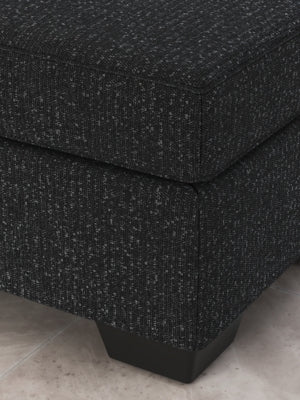 Ashley Furniture Jasmine Peaks Ottoman featuring beige fabric upholstery and wooden block legs.