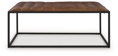 Ashley Furniture Junsor coffee table ottoman with a cushioned top and wooden legs, ideal for living room seating and decor.