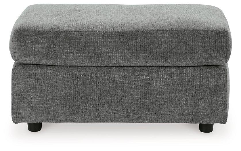 Ashley Furniture Stairatt Ottoman in neutral fabric with plush cushioning and wooden legs, used as a versatile footrest or side table.