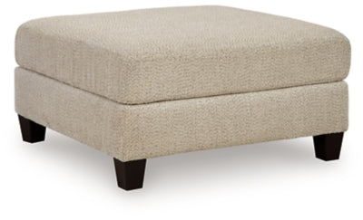 Ashley Furniture Steelwater Retreat oversized accent ottoman with plush fabric and wooden legs, shown from an angled view.