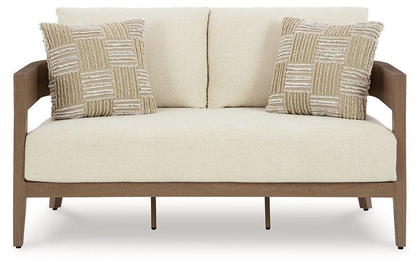 Ashley Furniture Serene Bay outdoor loveseat with beige cushions, featuring a sturdy metal frame and comfortable seating for outdoor spaces.
