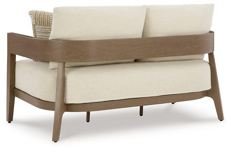 Outdoor loveseat with cushions from Ashley Furniture, featuring a stylish design and comfortable seating for outdoor spaces.