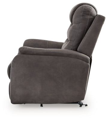 Ashley Furniture Snowfield Power Lift Recliner showing a plush, grey fabric recliner with a side control panel and padded armrests.