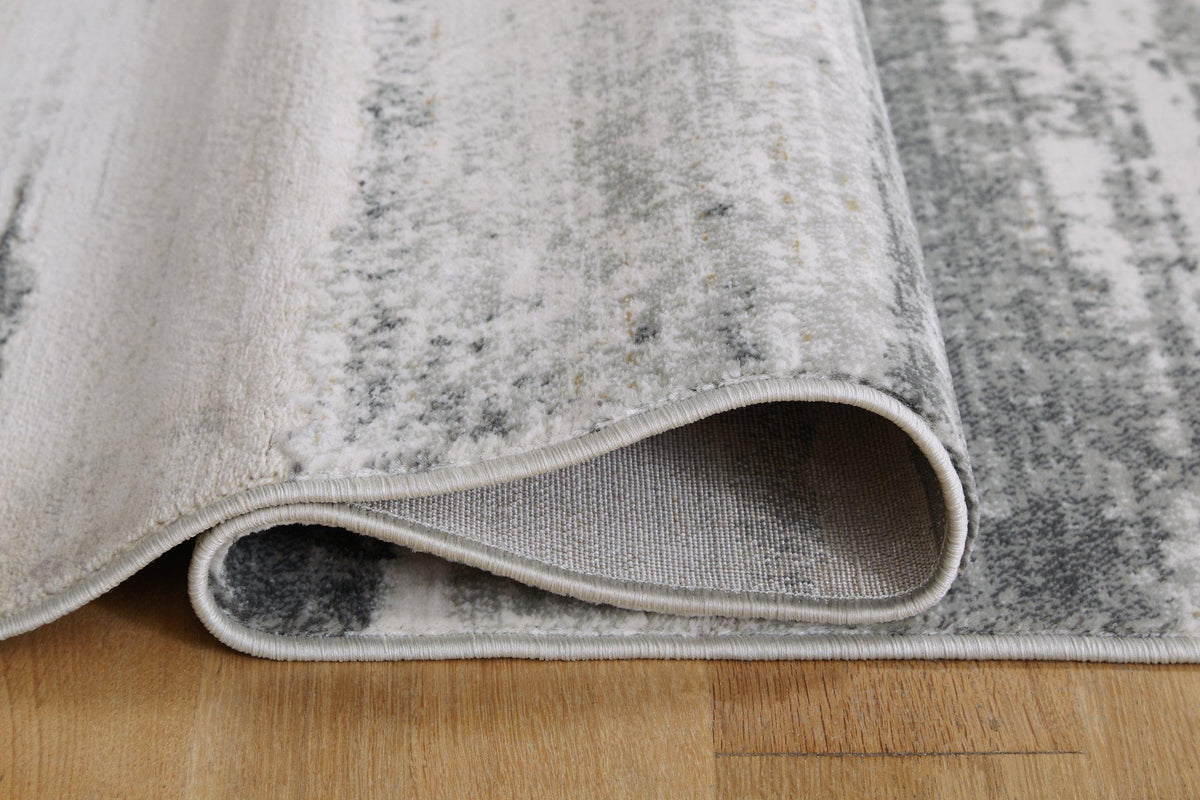 Soft beige Abanett rug by Ashley Furniture with intricate patterns, perfect for adding warmth to living room or bedroom floors.
