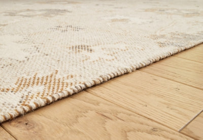 Close-up of the textured Calkin Rug by Ashley Furniture, showcasing intricate woven patterns and rich neutral tones.