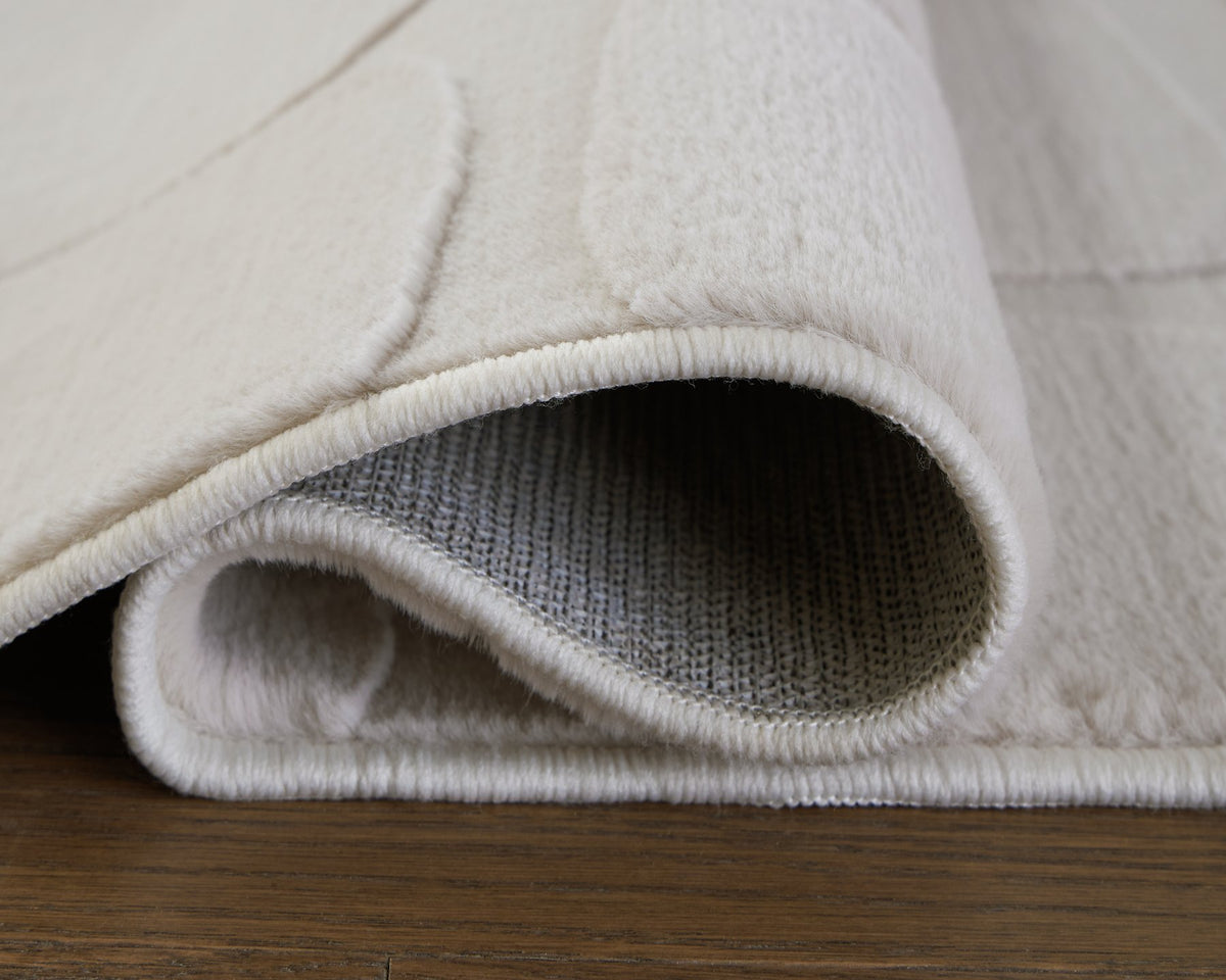 Medium washable area rug from Ashley Furniture with a detailed pattern in neutral tones, suitable for living spaces.