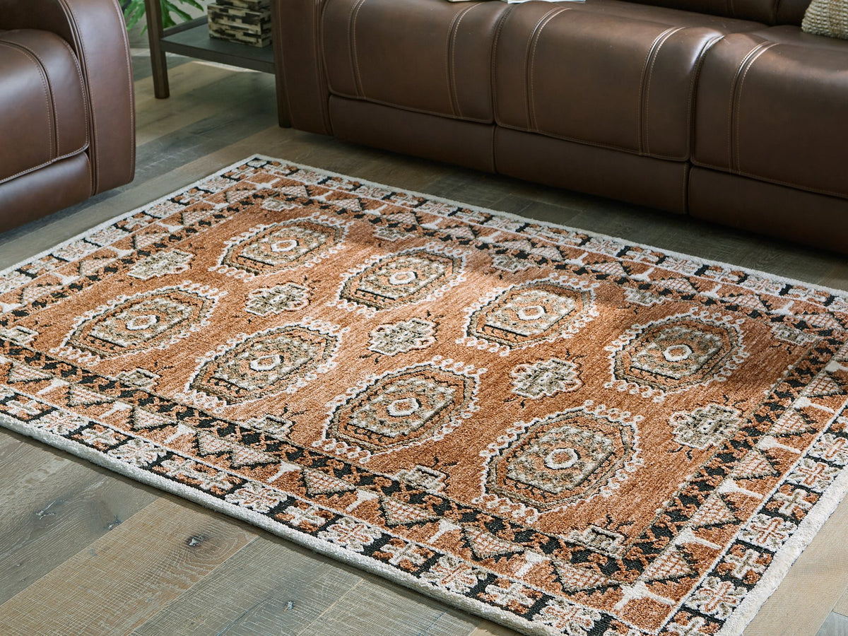 Medium Ashley Furniture Qaabiz Area Rug with intricate patterns in neutral tones, cropped view highlighting texture and design.