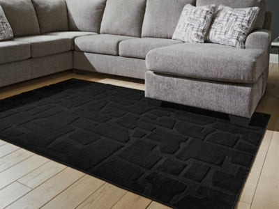 Medium Ashley Furniture Gibbswell washable 5x7 area rug with a detailed, textured pattern on a neutral background.