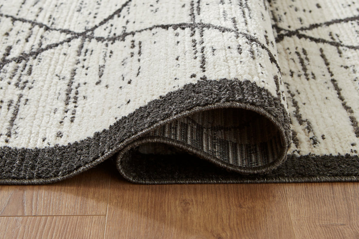 Close-up of the Fenriston Rug by Ashley Furniture, showcasing its intricate woven pattern and textured surface.