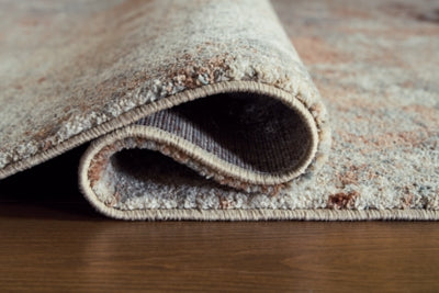 Close-up of the Ashley Furniture Jadenburg Rug showing intricate patterns and rich texture in neutral tones.