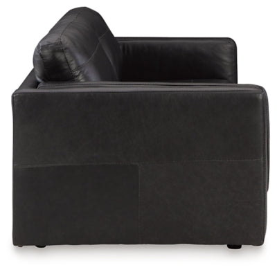 Ashley Furniture Amiata sofa with beige upholstery and plush cushions, shown from a side angle in a modern living room setting.