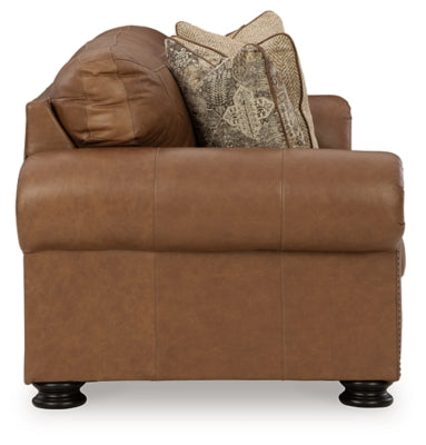 Ashley Furniture Carianna Sofa with plush cushions and wooden legs, shown from the side view.