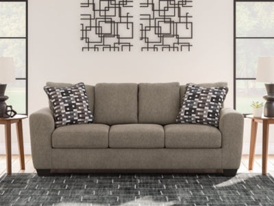 Ashley Furniture Triston-Peaks sofa with plush cushions and neutral fabric, shown in a cozy living room setting.