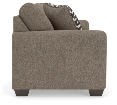 Ashley Furniture Triston-Peaks sofa with plush fabric, showing a side view with soft cushions and wooden legs.