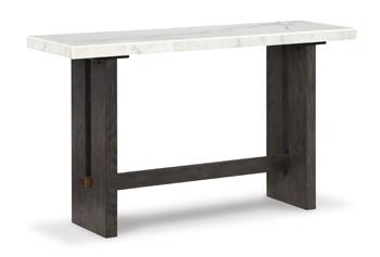 Ashley Furniture Burkhaus sofa table with a sleek wooden surface and modern design, placed beside a living room sofa.
