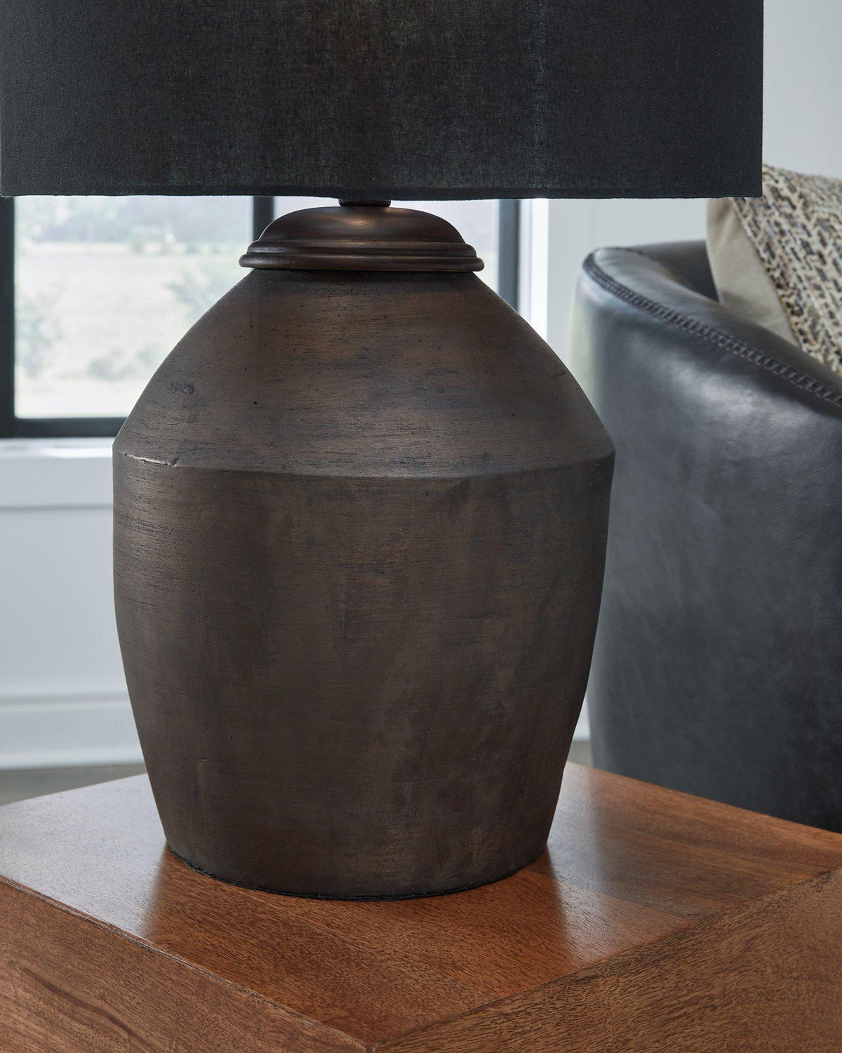 Naareman table lamp by Ashley Furniture with a sleek ceramic base and fabric shade, placed on a wooden bedside table.