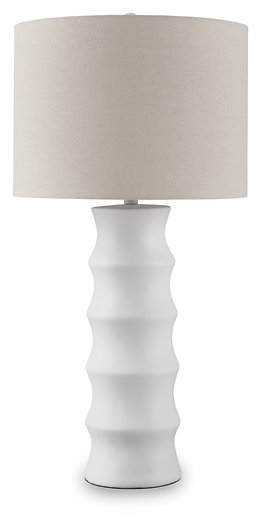 Ashley Furniture Veraleigh table lamp with a beige fabric shade and a dark bronze base, sitting on a wooden side table.