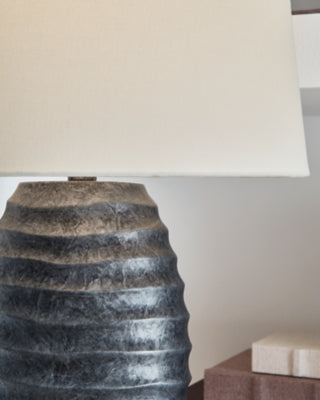 Pair of Ashley Furniture Caronick table lamps with beige fabric shades and dark wood bases, ideal for bedside or living room decor.
