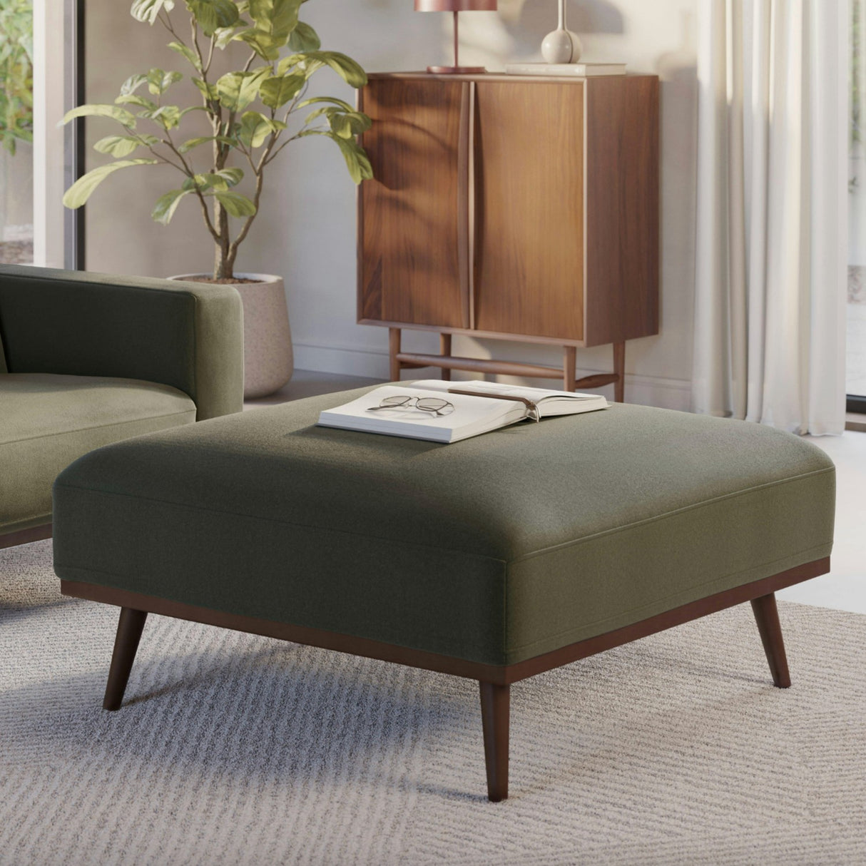 Felted green MCM-style square ottoman by Article with soft, textured felted surface and sturdy wooden legs for modern decor.