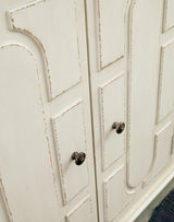 Ashley Roranville accent cabinet with wooden finish, featuring storage drawers and decorative details for living room or hallway.