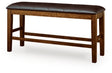 Ashley Furniture Ralene counter height dining bench with wooden legs and upholstered seat, shown from an angled side view.