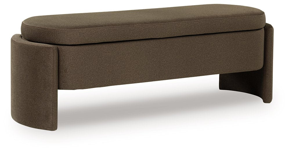 Ashley Furniture Vavuniya Storage Bench featuring a wooden frame and cushioned top, shown from an angled side view.