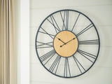 Ashley Furniture Brockett wall clock with a round face and modern design, featuring black numerals and sleek metal frame.
