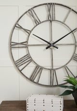 Ashley Furniture Paquita Wall Clock showing a sleek round design with black hour and minute hands on a light background.
