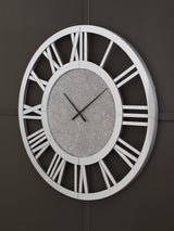 Ashley Furniture Reinport wall clock with a modern round design and black frame, hanging on a neutral-colored wall.