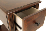 Ashley Furniture Breegin chairside end table with wood finish and storage drawer, designed for convenient placement beside a chair.