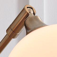 Taliya Arc Floor Lamp by Ashley Furniture with a sleek curved design and modern metal finish in a stylish living room setting