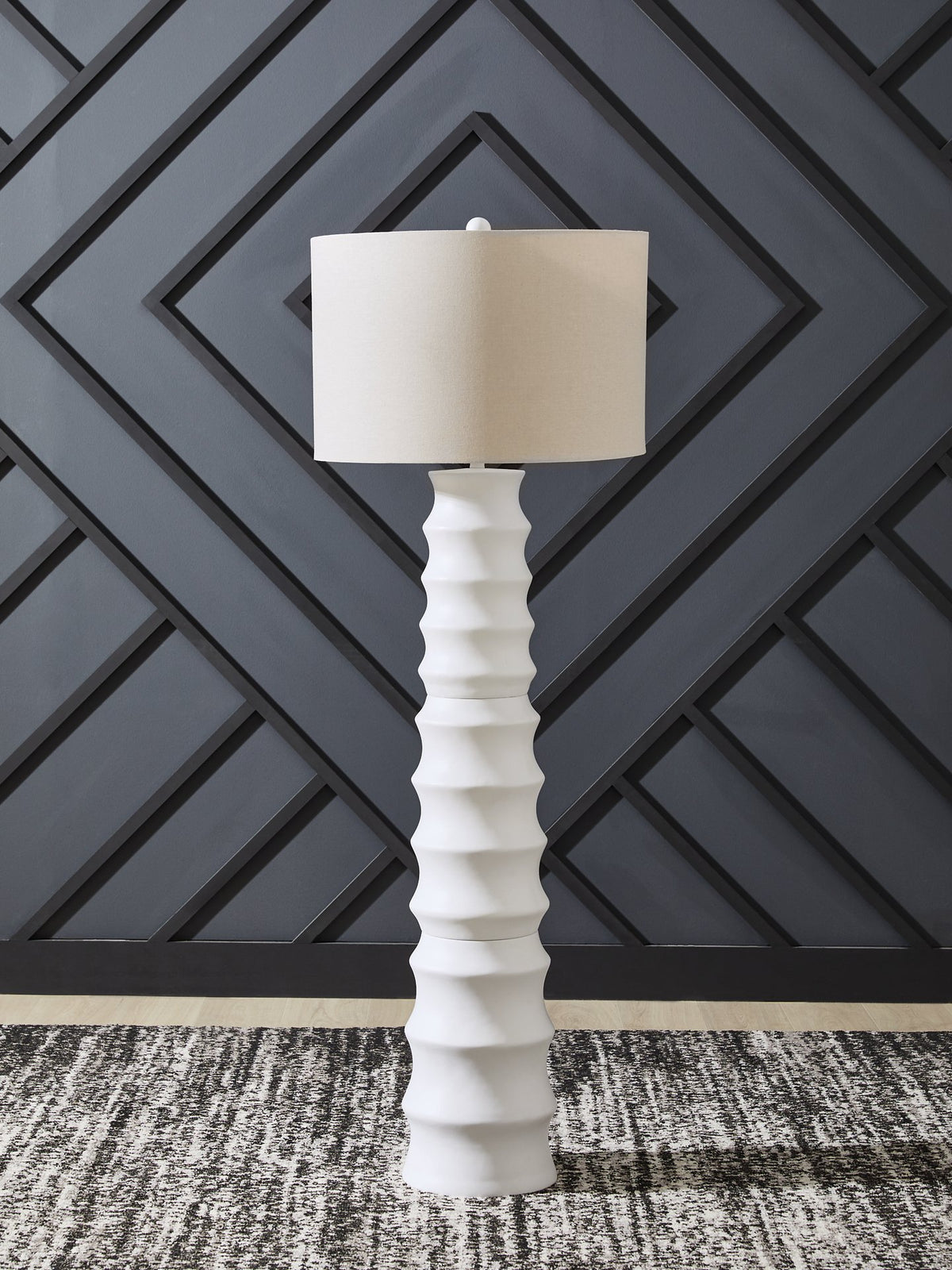Ashley Furniture Veraleigh floor lamp with a sleek metal base and fabric shade, standing upright in a modern living room setting.