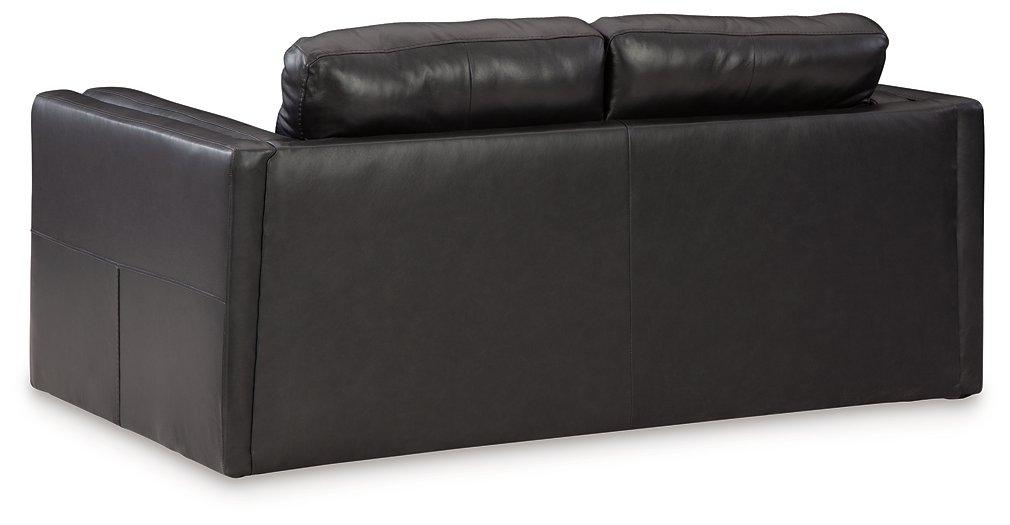 A beige Ashley Furniture Amiata loveseat with plush cushions and wooden legs, shown in a cozy living room setting.