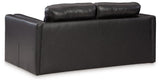A beige Ashley Furniture Amiata loveseat with plush cushions and wooden legs, shown in a cozy living room setting.