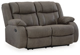 Ashley Furniture First Base reclining loveseat with plush cushions and a neutral fabric upholstery, shown from an angled view.