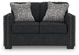Ashley Furniture Jasmine Peaks loveseat showing plush beige upholstery and cushioned armrests, ideal for cozy living room seating.