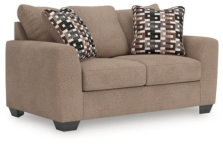 Ashley Furniture Triston-Peaks loveseat with plush cushions and wooden legs, shown from an angled view.