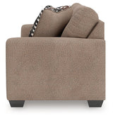 Ashley Furniture Triston-Peaks loveseat with plush fabric and cushioned armrests, shown from a side view.