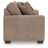 Ashley Furniture Triston-Peaks loveseat with plush fabric and cushioned armrests, shown from a side angle.
